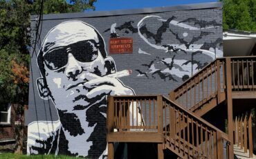 A mural of a man smoking a cigarette on the side of a building.